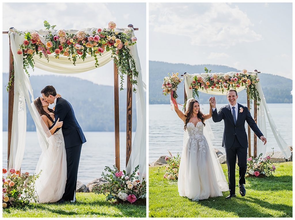 Bride and Groom kissing under a flower arch after wedding ceremony at The Lodge at Whitefish Lake with the lake and tree covered hills behind them